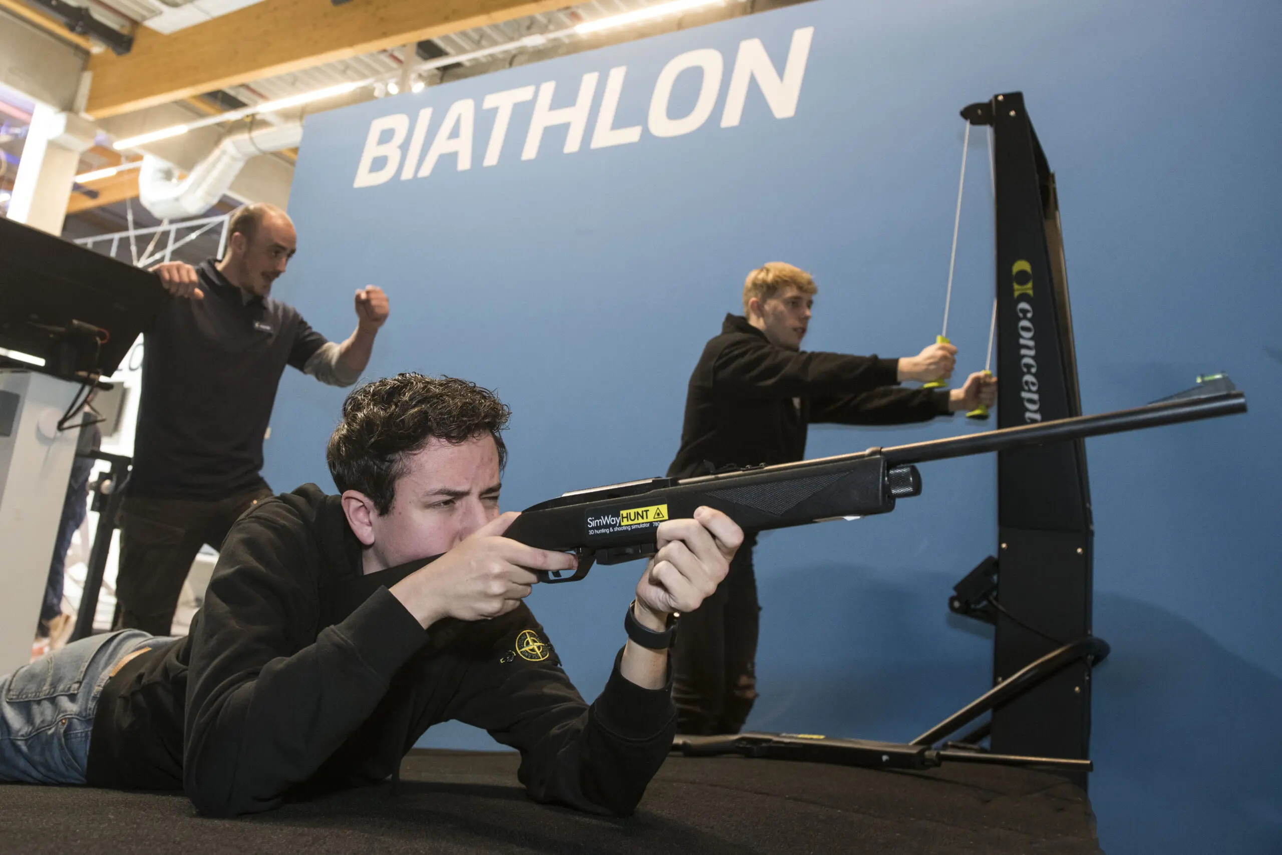 Spelers schieten liggend met een geweer op de biatlonbaan