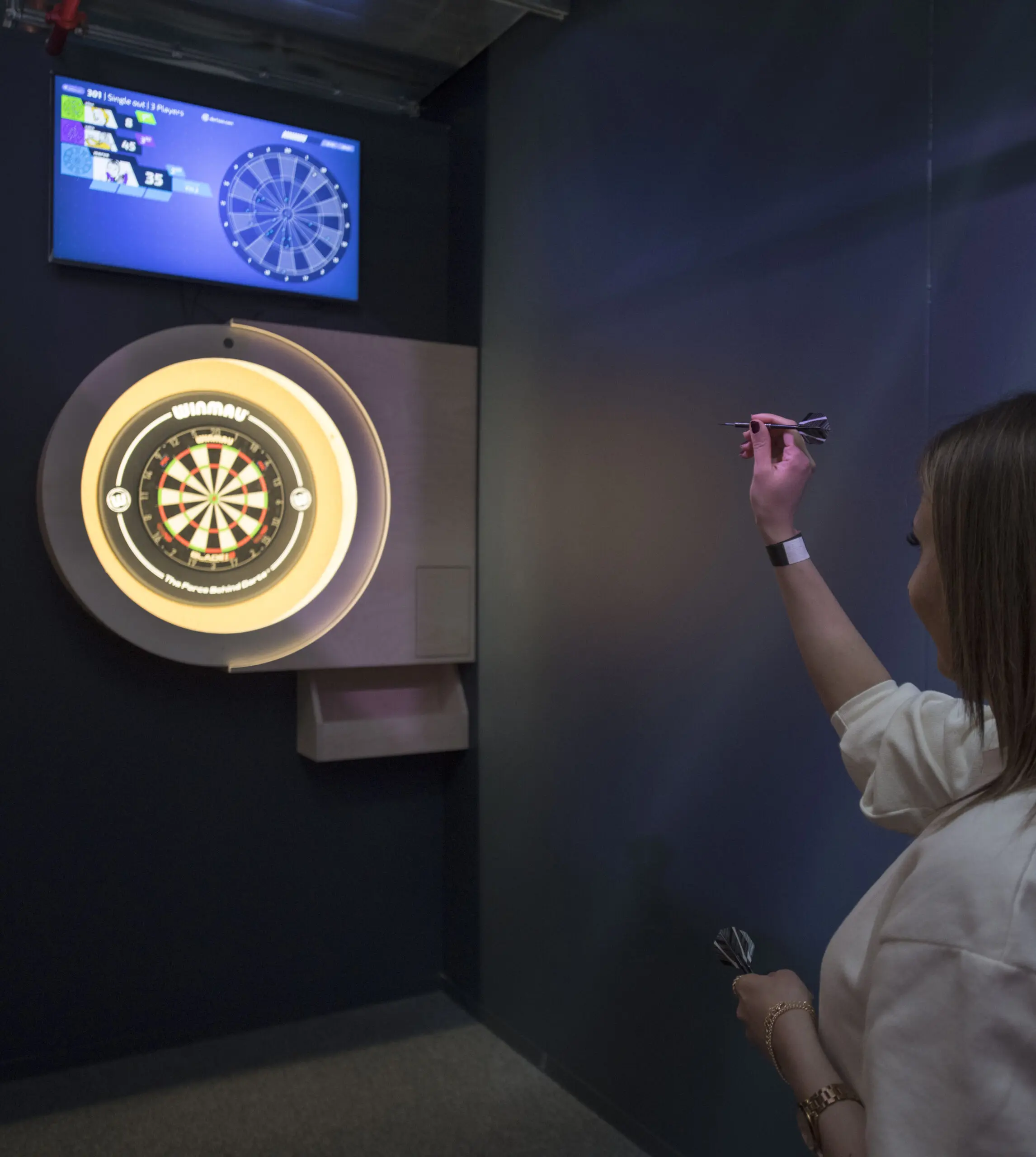 Vrouw gooit een pijl op het interactieve dartbord met scorescherm
