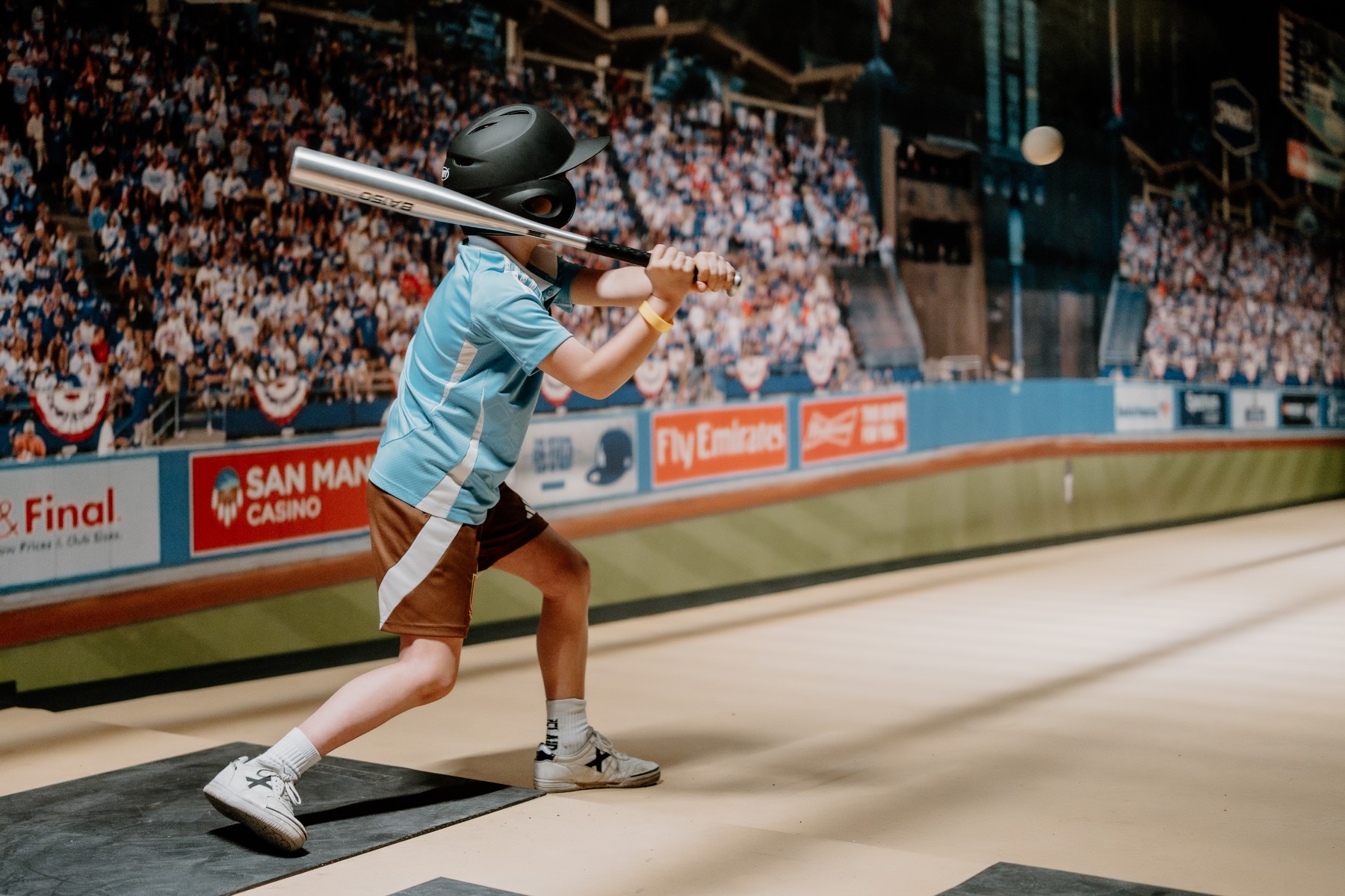 Jongen raakt de bal in de batting cage voor een stadionscherm