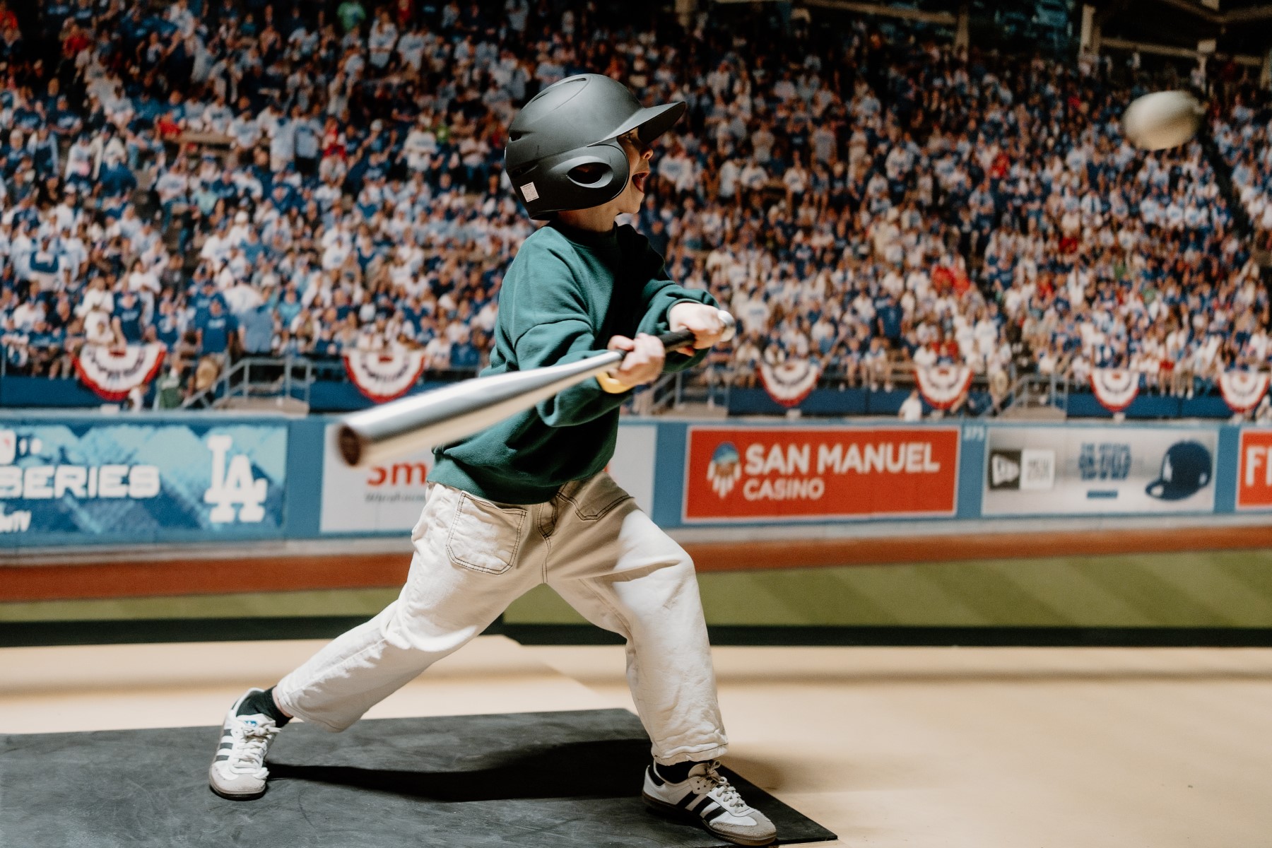 Jongen met helm maakt een swing in de batting cage