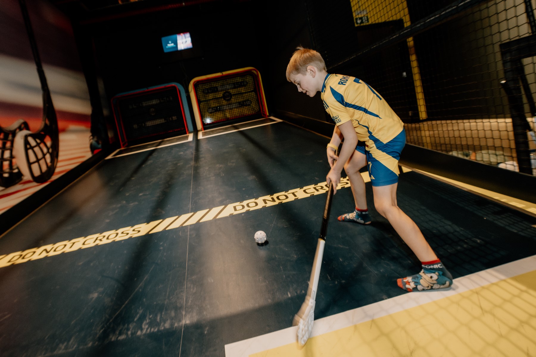 Jongen dribbelt met stick en bal op het floorballveld