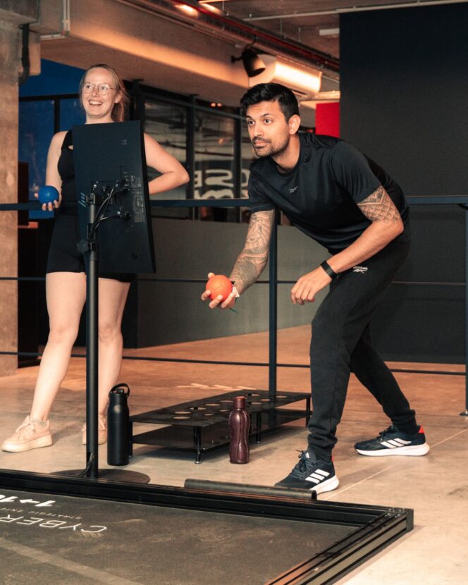 Twee spelers mikken ballen op een interactieve vloerbaan in de Black Box