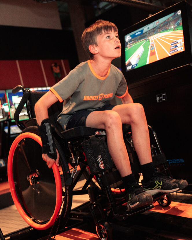 Jongen rijdt in een sportrolstoel voor het racescherm